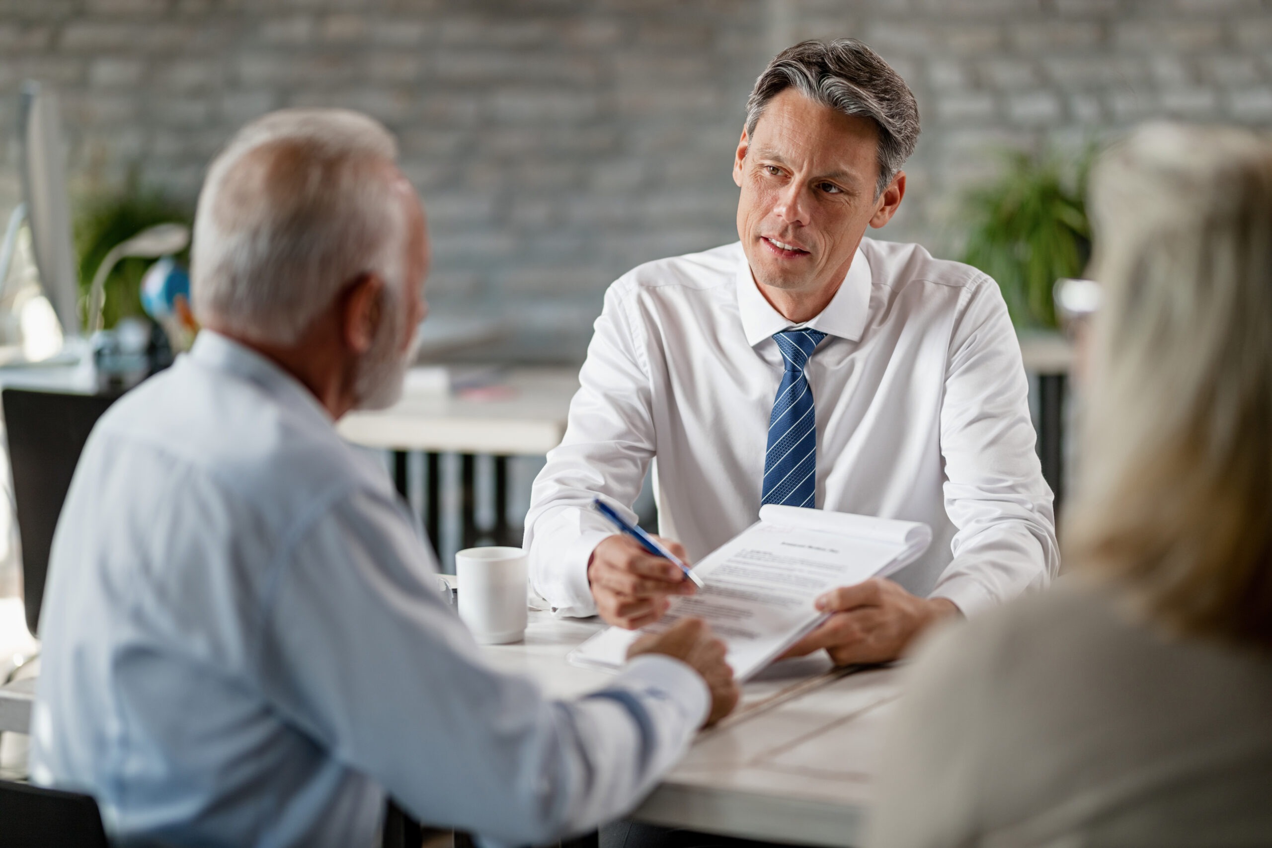 Lawyer reviewing estate planning documents with older couple in office