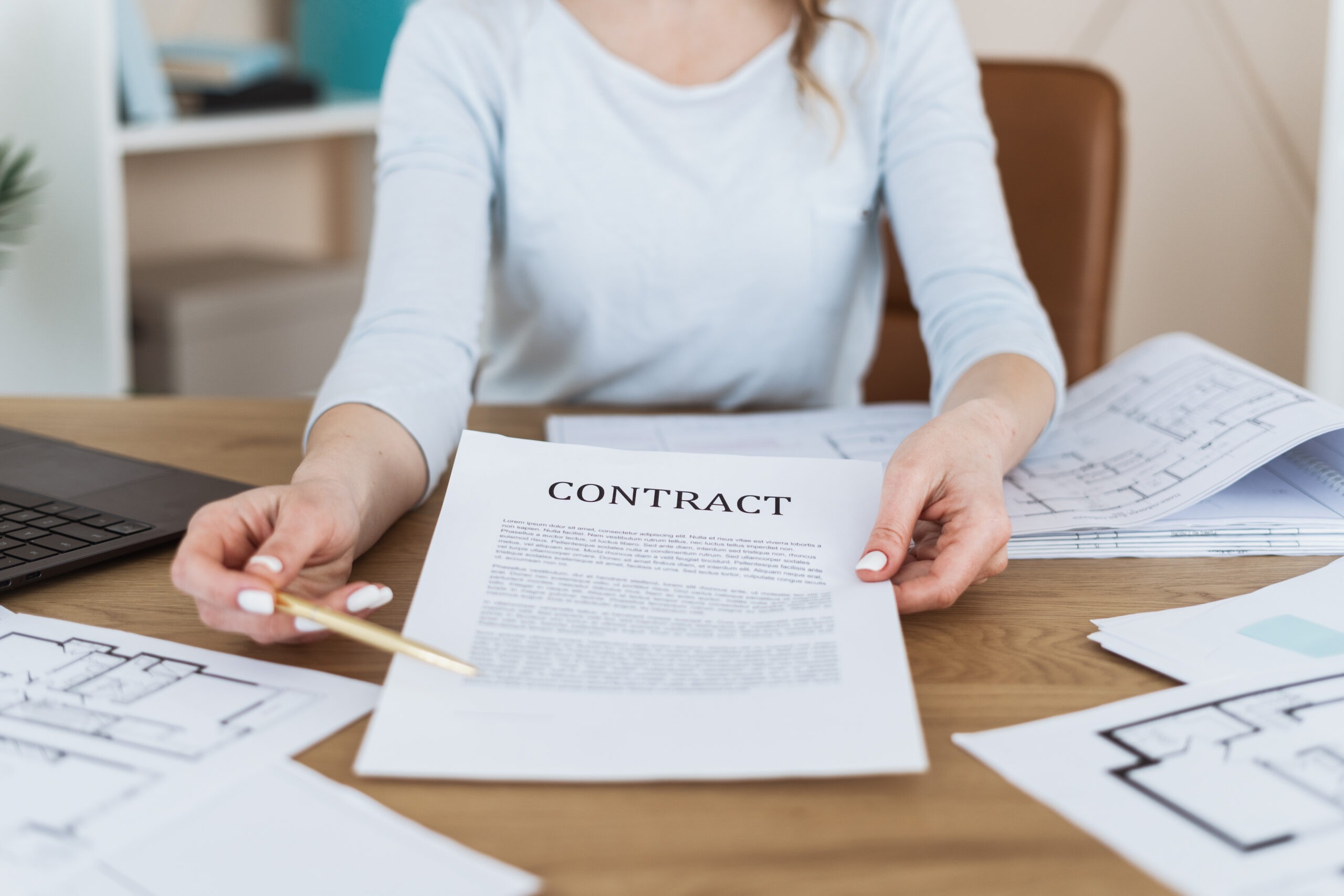 Woman reviewing mortgage contract at desk with pen and documents